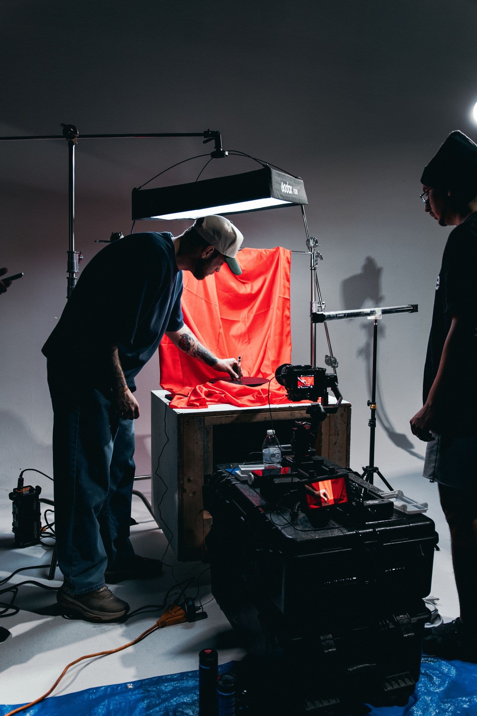 Crew lighting a tabletop set in a studio, cables and stands around them