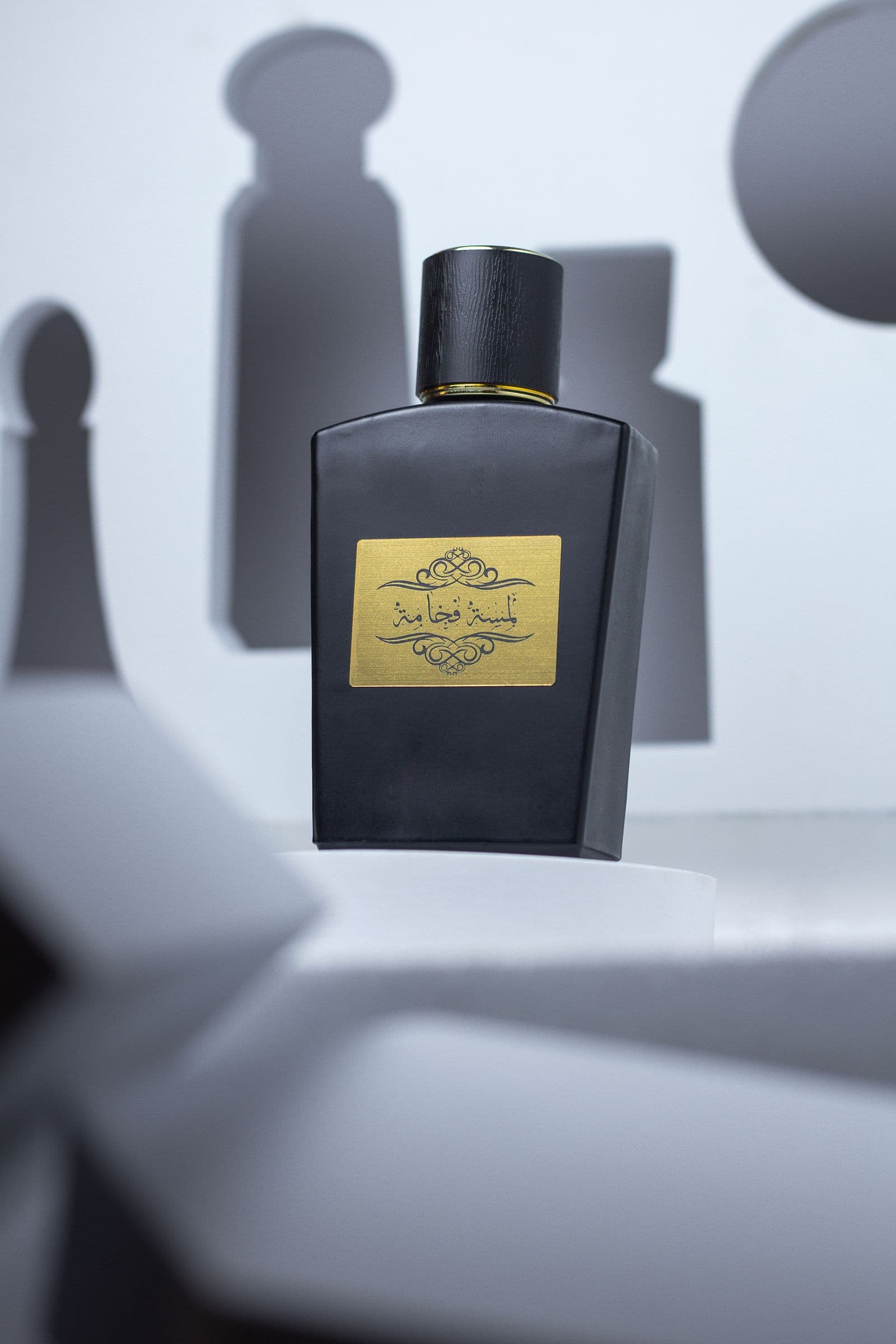 Black fragrance bottle with a gold label on sculpted white forms